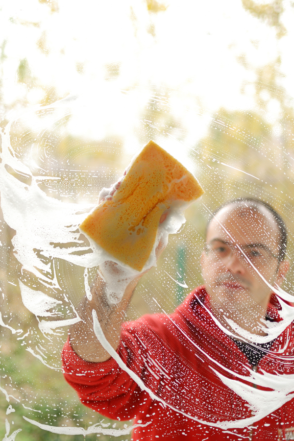 Man washing windows with sudsy solution -clean windows fast